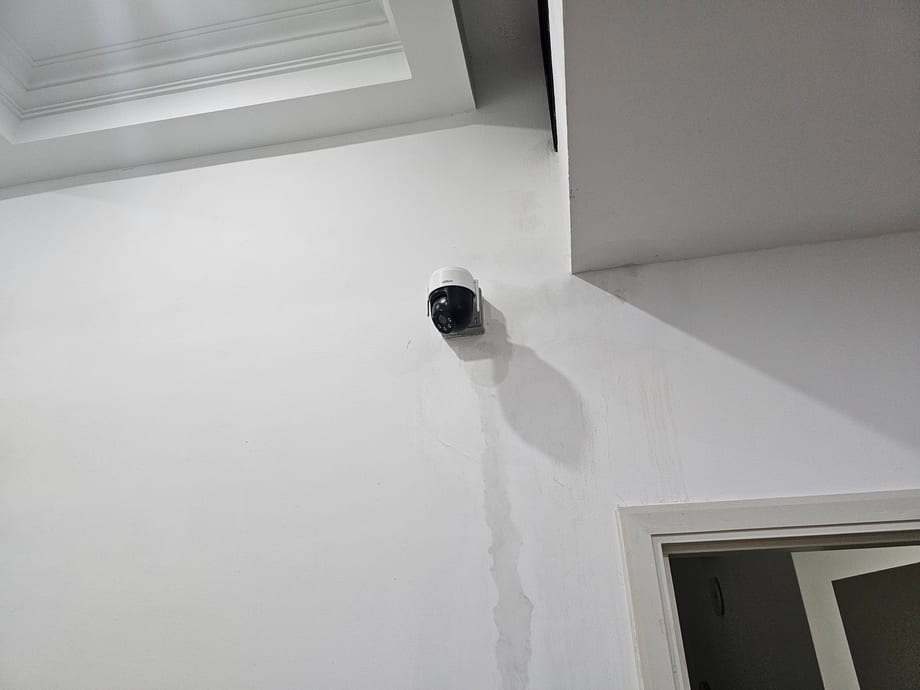 A dome camera on a white ceiling above an interior doorway.